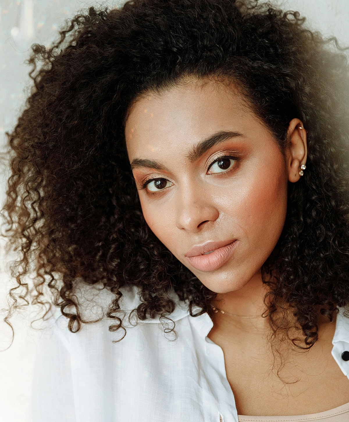 Smiling woman in white lingerie on light background.