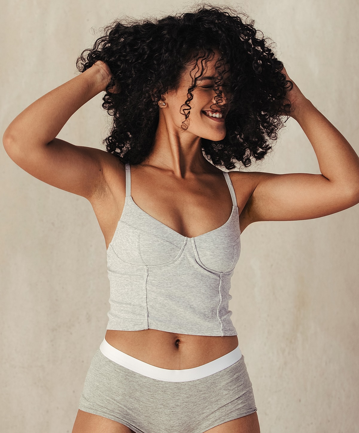 Smiling woman with curly hair in casual clothing.