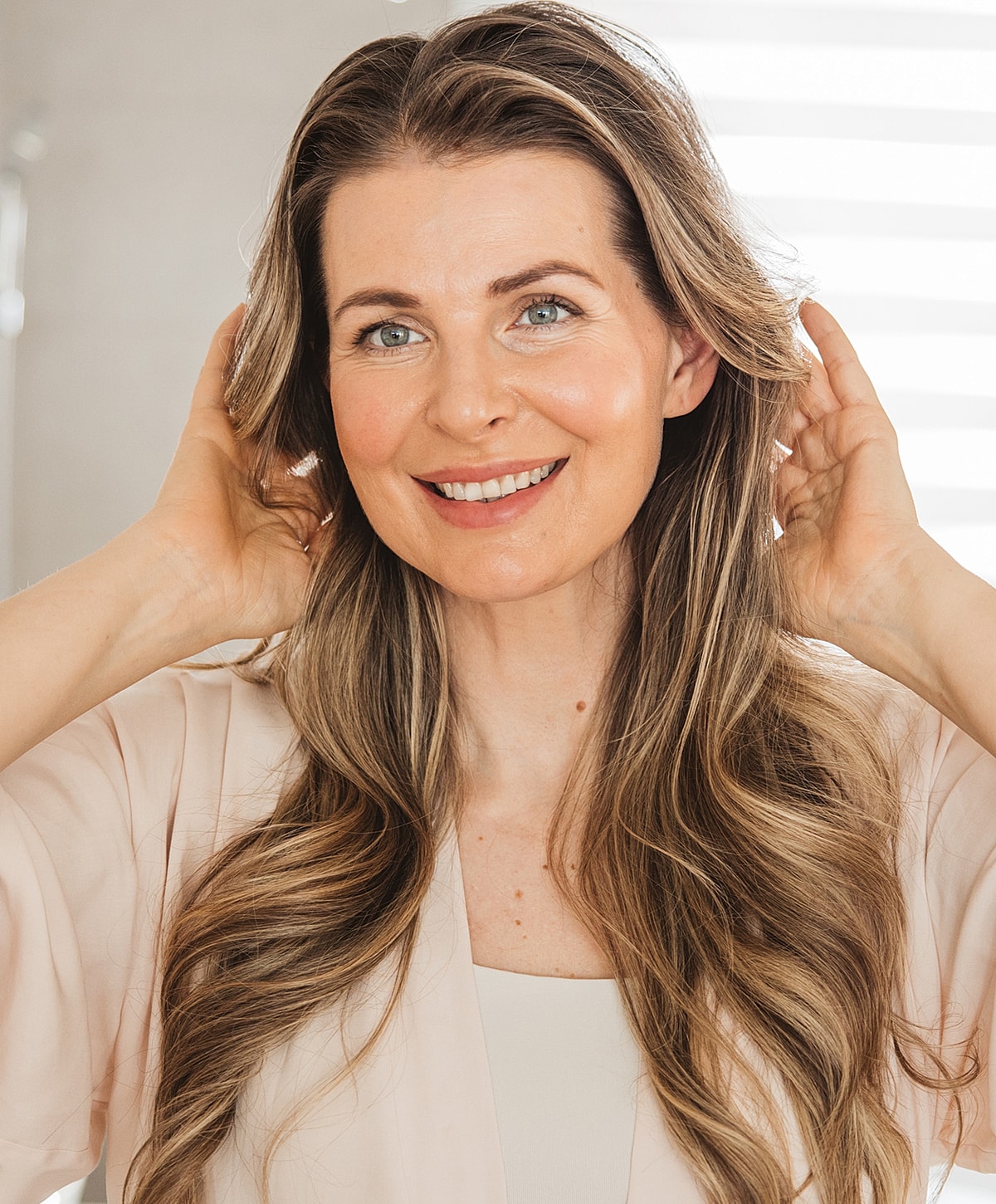 Smiling woman with long wavy hair in robe.