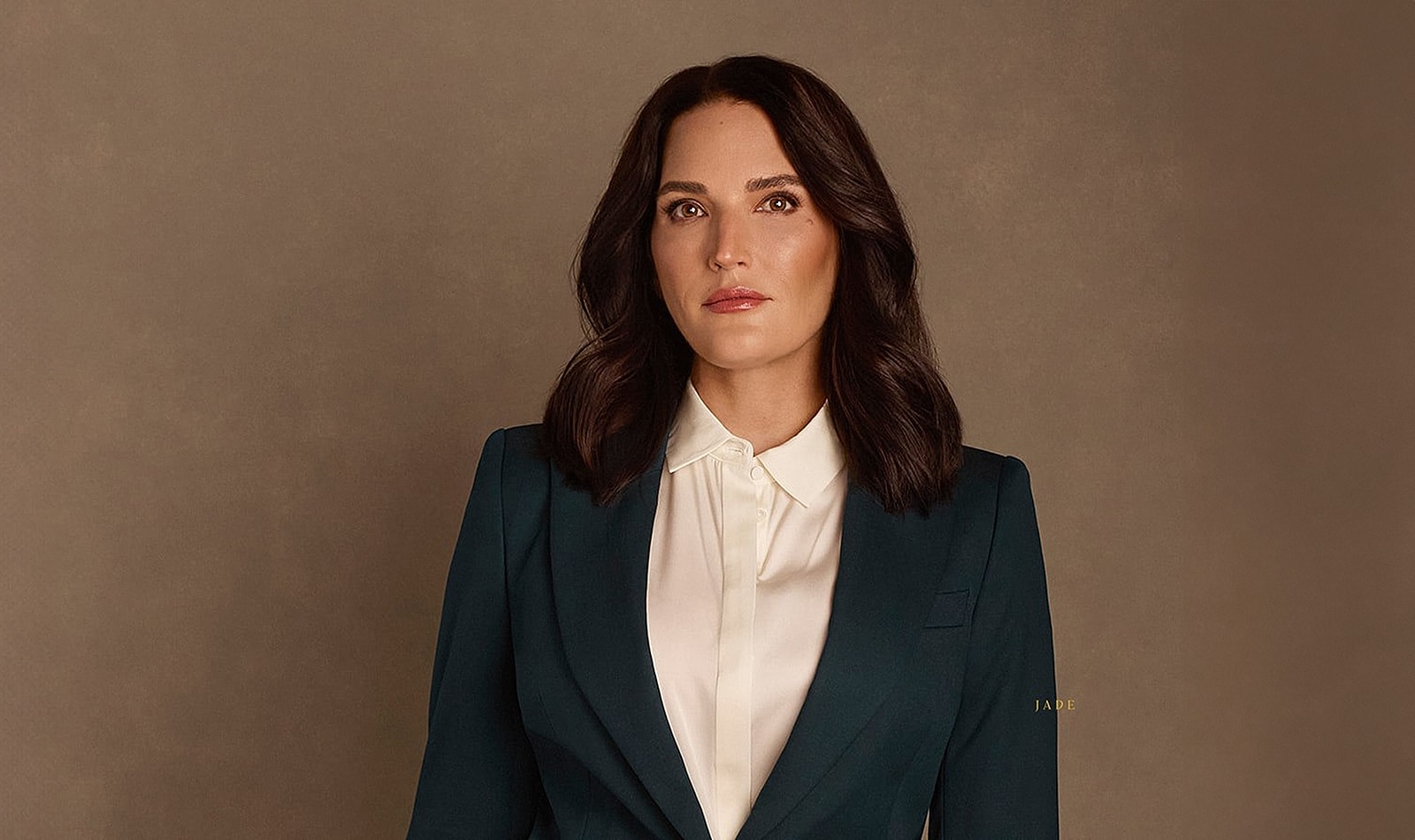 Woman in black blazer and lingerie, posing confidently.